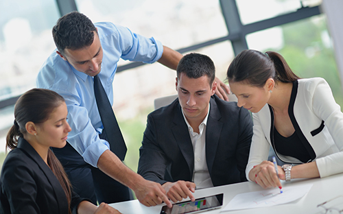 A group of four people look together at a tablet.