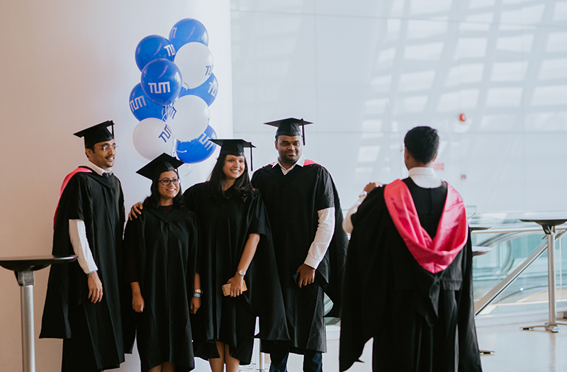 Four TUM graduates take a group photo with TUM balloons.