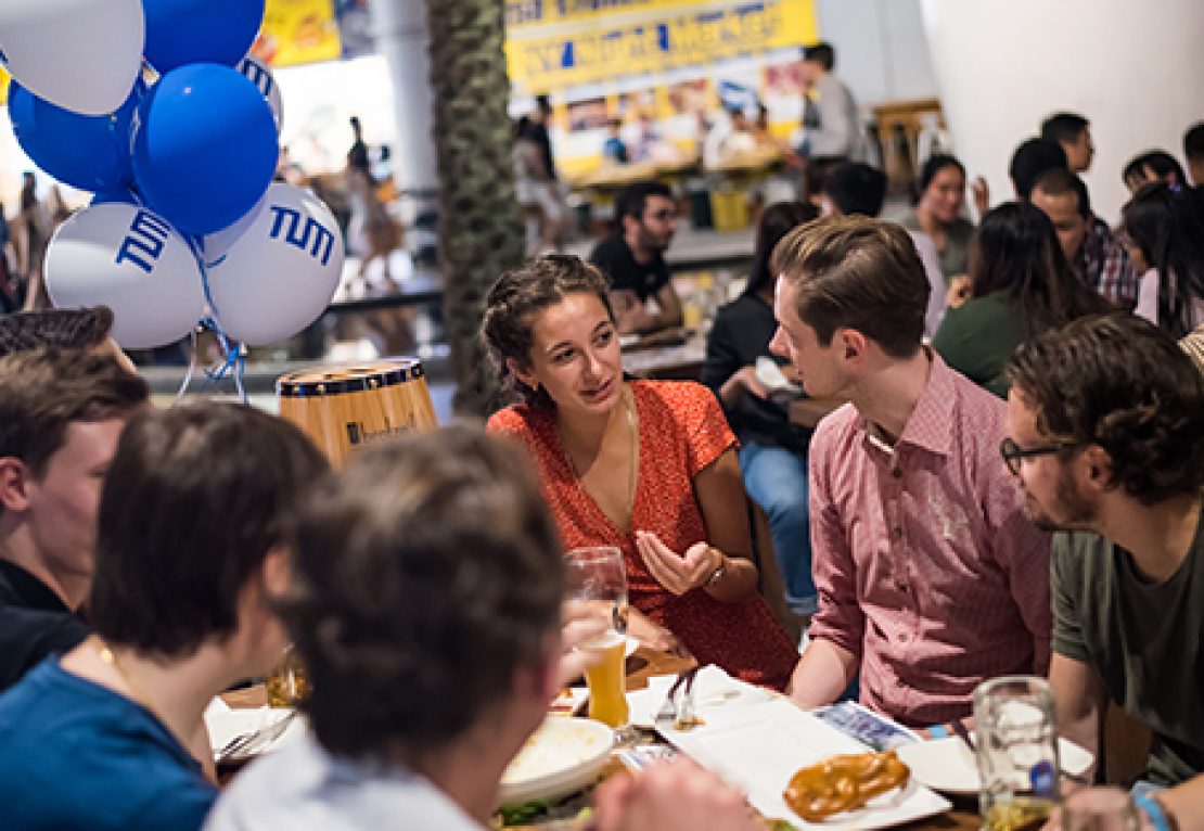 Alumni miteinander im Gespräch an einem Biertisch.