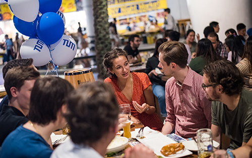 Alumni miteinander im Gespräch an einem Biertisch.