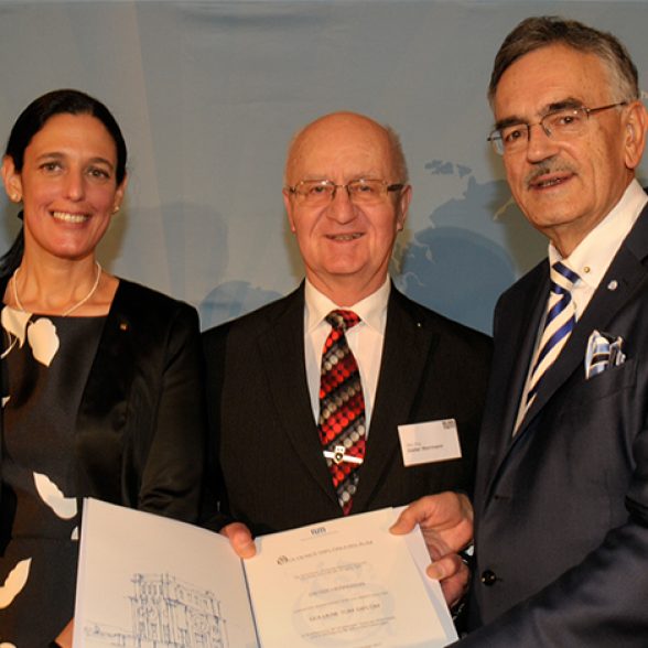 President Wolfgang A. Herrmann (r.) and Vice-President Dr. Ana Santos Kühn hand over the golden degree deed to gold degree holder Dieter Herrmann.