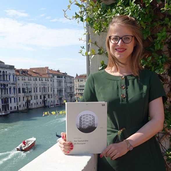 TUM Alumna Barbara Berger with her printed dissertation at the German Study Center in Venice.