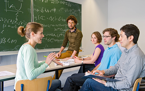 Studierendengruppe vor einer Tafel bei einer Besprechung.