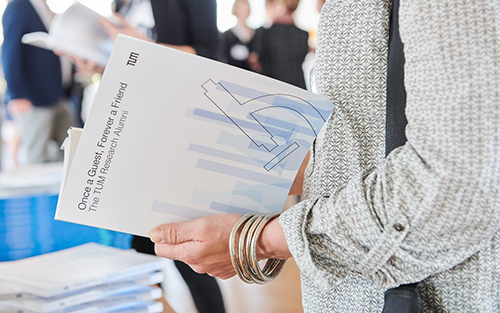 A woman is leafing through the research alumni brochure.