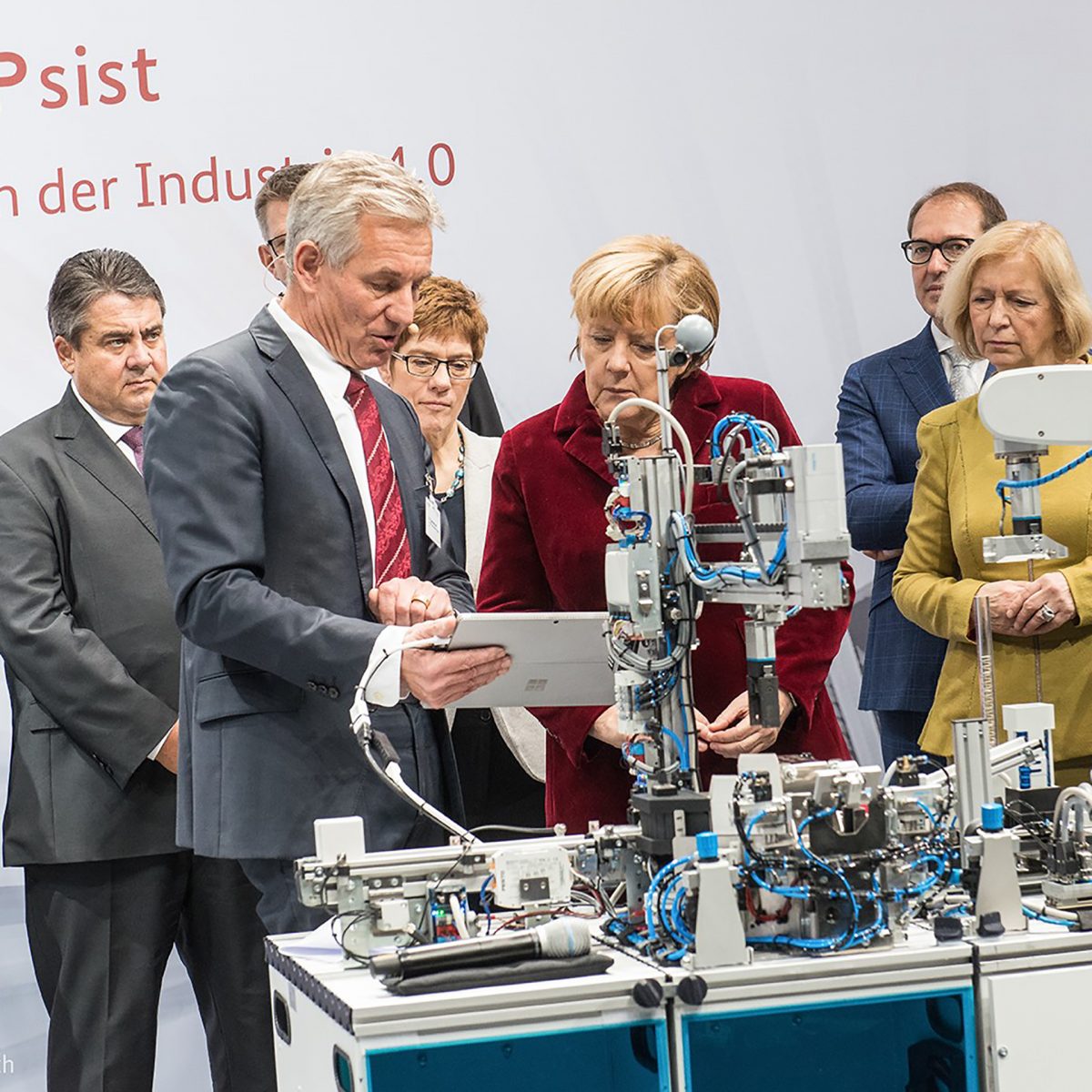 Eberhard Veit and Angela Merkel discuss in front of a technical device.