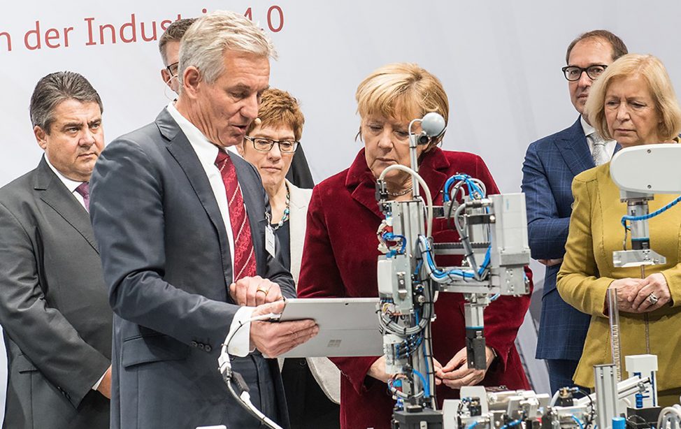 Eberhard Veit and Angela Merkel discuss in front of a technical device.