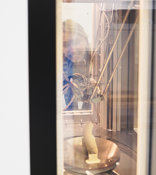 Gründerin Miriam Harst blickt in den Innenraum des 3-D-Druckers von Kumovis, in dem gerade ein Knochenimplantat hergestellt wird.