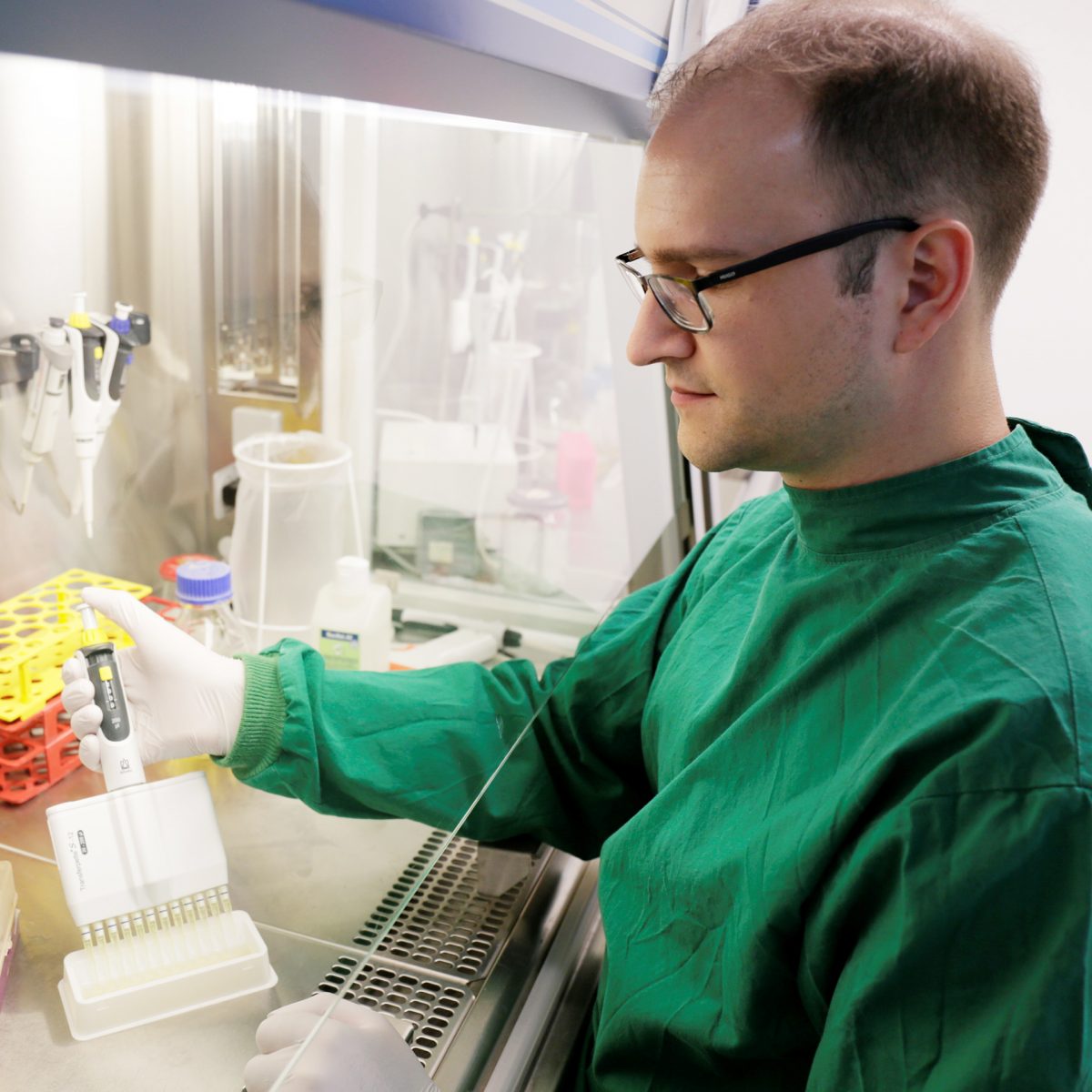 TUM Alumni Robert Macsics working at his laminar flow cabinet in TUM's S2-Lab.