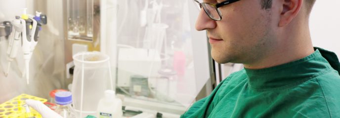 TUM Alumnus Robert Macsics beim Arbeiten an einer Sterilbank im S2-Labor der TUM.