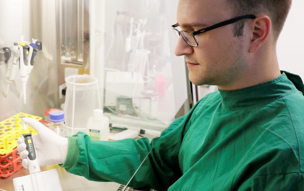 TUM Alumnus Robert Macsics beim Arbeiten an einer Sterilbank im S2-Labor der TUM.