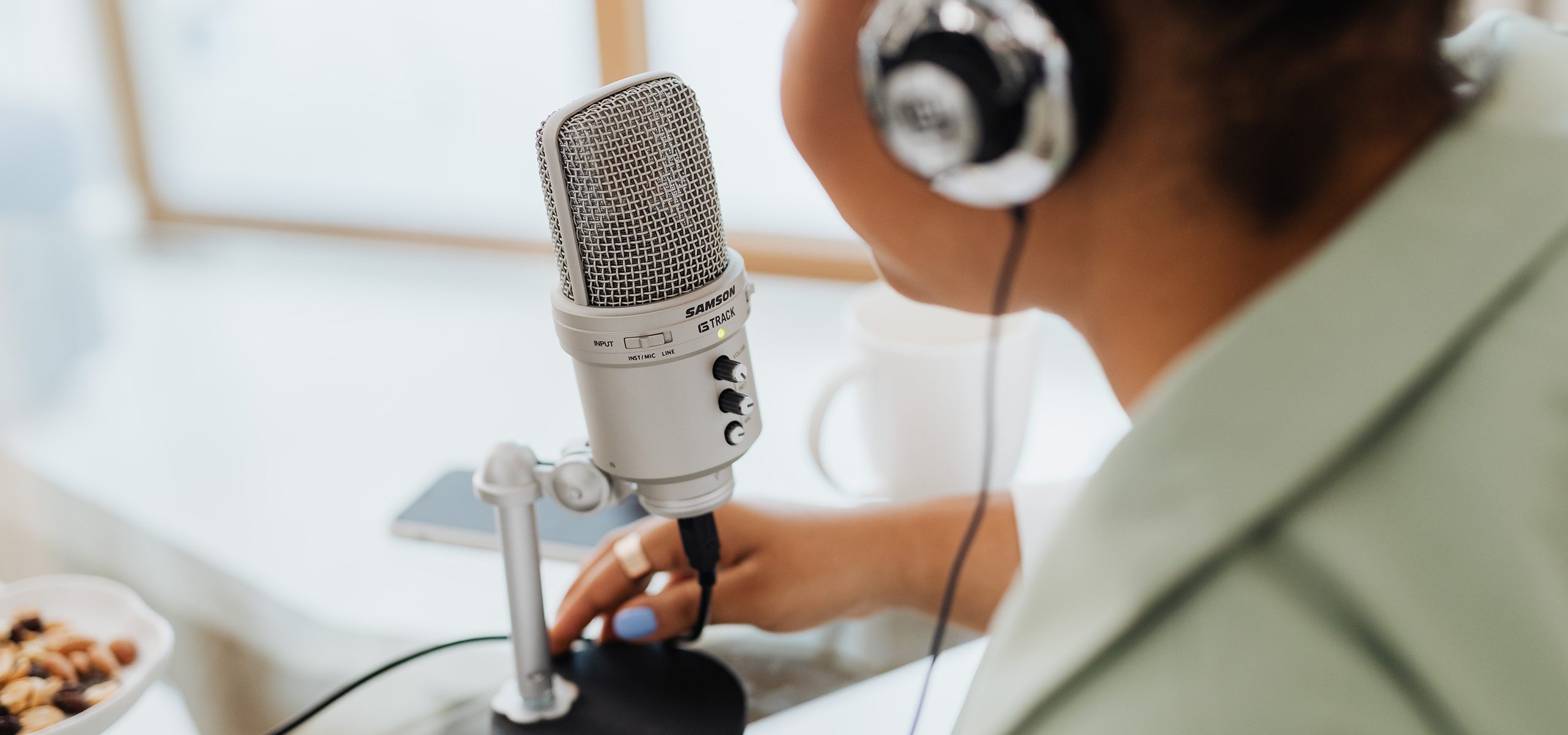 A woman wearing headphones speaks into a podcast microphone.