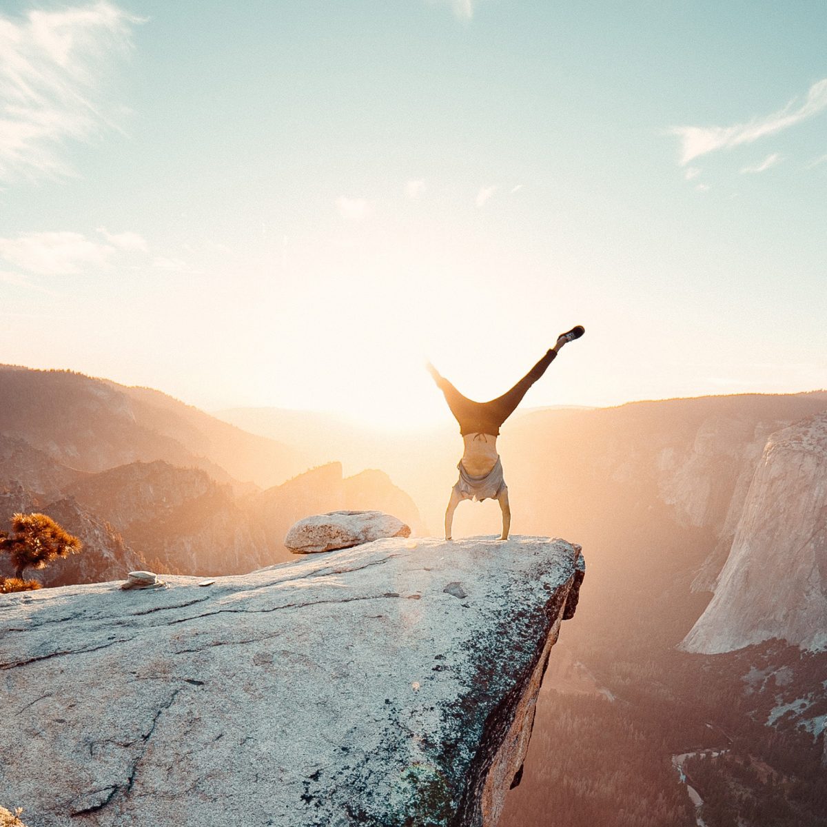 A man is doing a handstand on a rock.