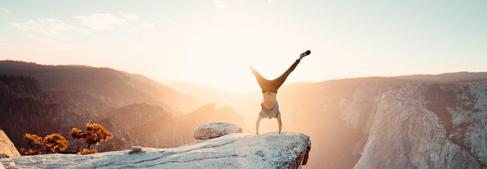 Ein Mann macht einen Handstand auf einem Felsen.