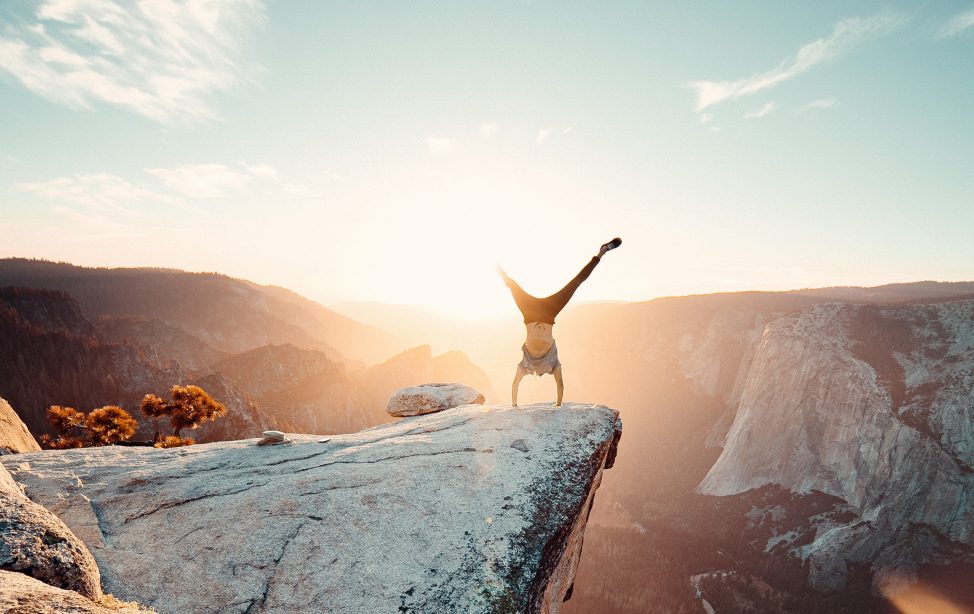 Ein Mann macht einen Handstand auf einem Felsen.