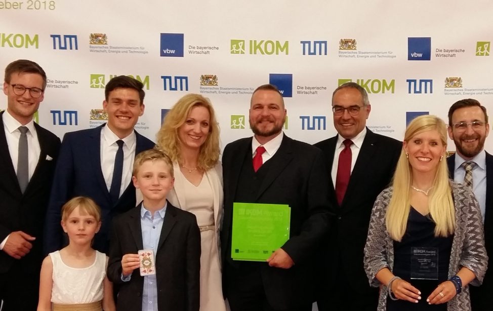 Gruppenbild vor IKOM-Fotowand: v.l.n.r.: Marius Beller und Niclas-Alexander Mauss (IKOM/TUM), Susanne Duschl, Andreas Duschl, TUM-Kanzler Albert Berger, Mitarbeiter Stefanie Gschwendtner, Alexander von Schneyder und Michaela Erben, vorne Leni und Anian Duschl.