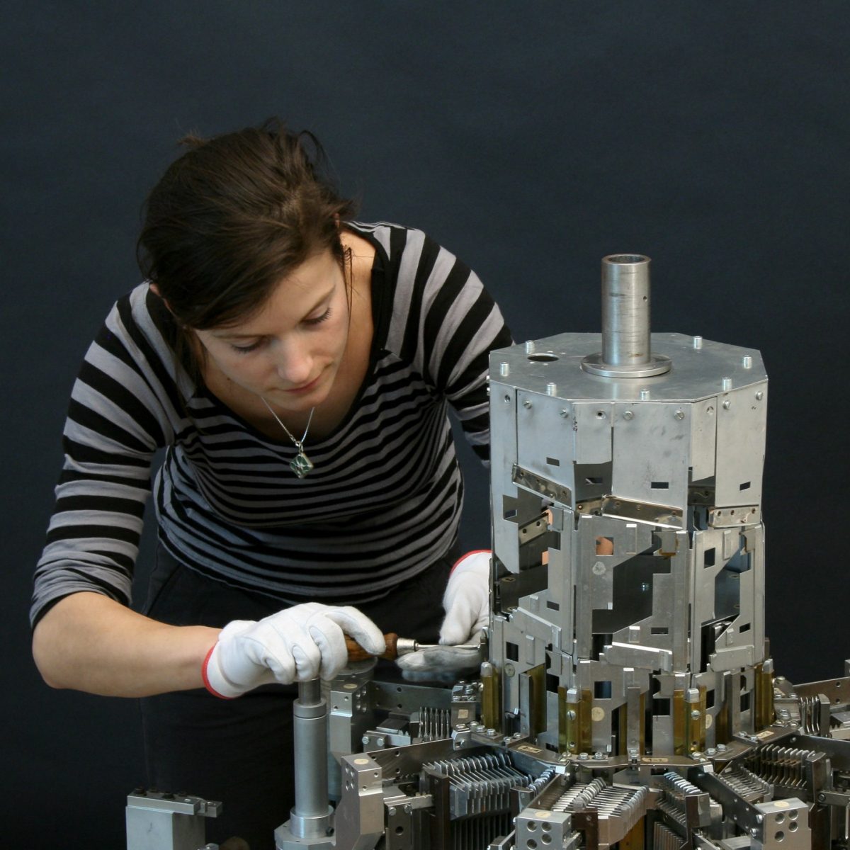 TUM alumna Dr. Nora Eibisch next to Konrad Zuse's helix tower in the workshop for scientific instruments of the Deutsches Museum.