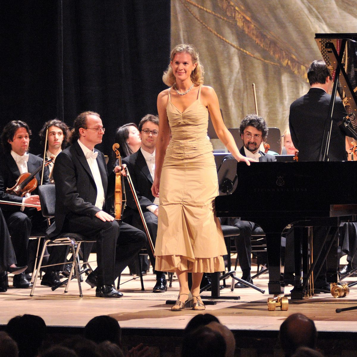 TUM Alumna Sylvia Dankesreiter mit Orchester auf der Bühne.