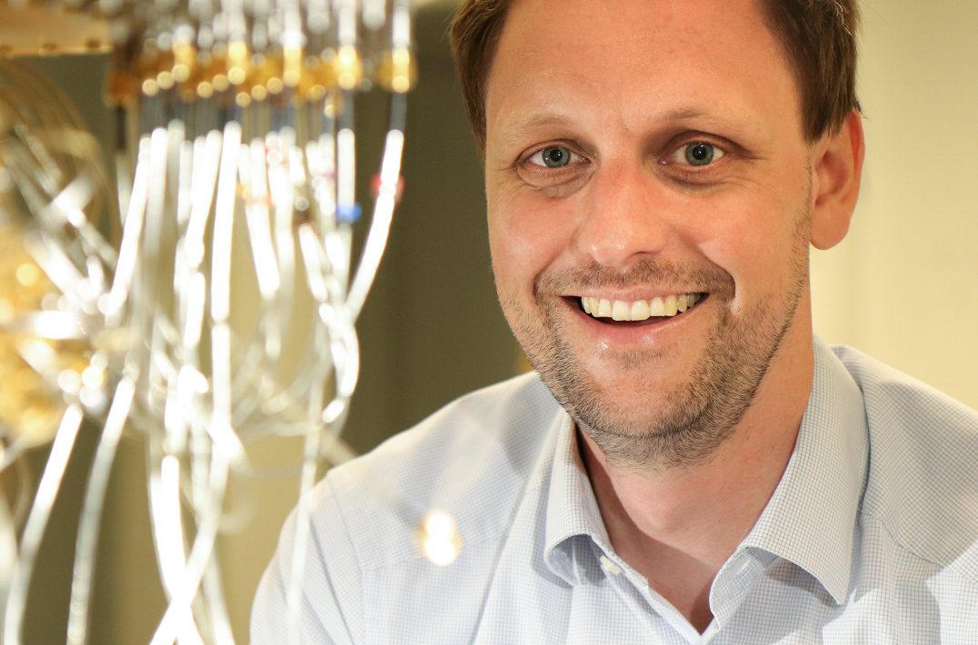 TUM alumnus Dr. Jan Goetz in front of a quantum computer.