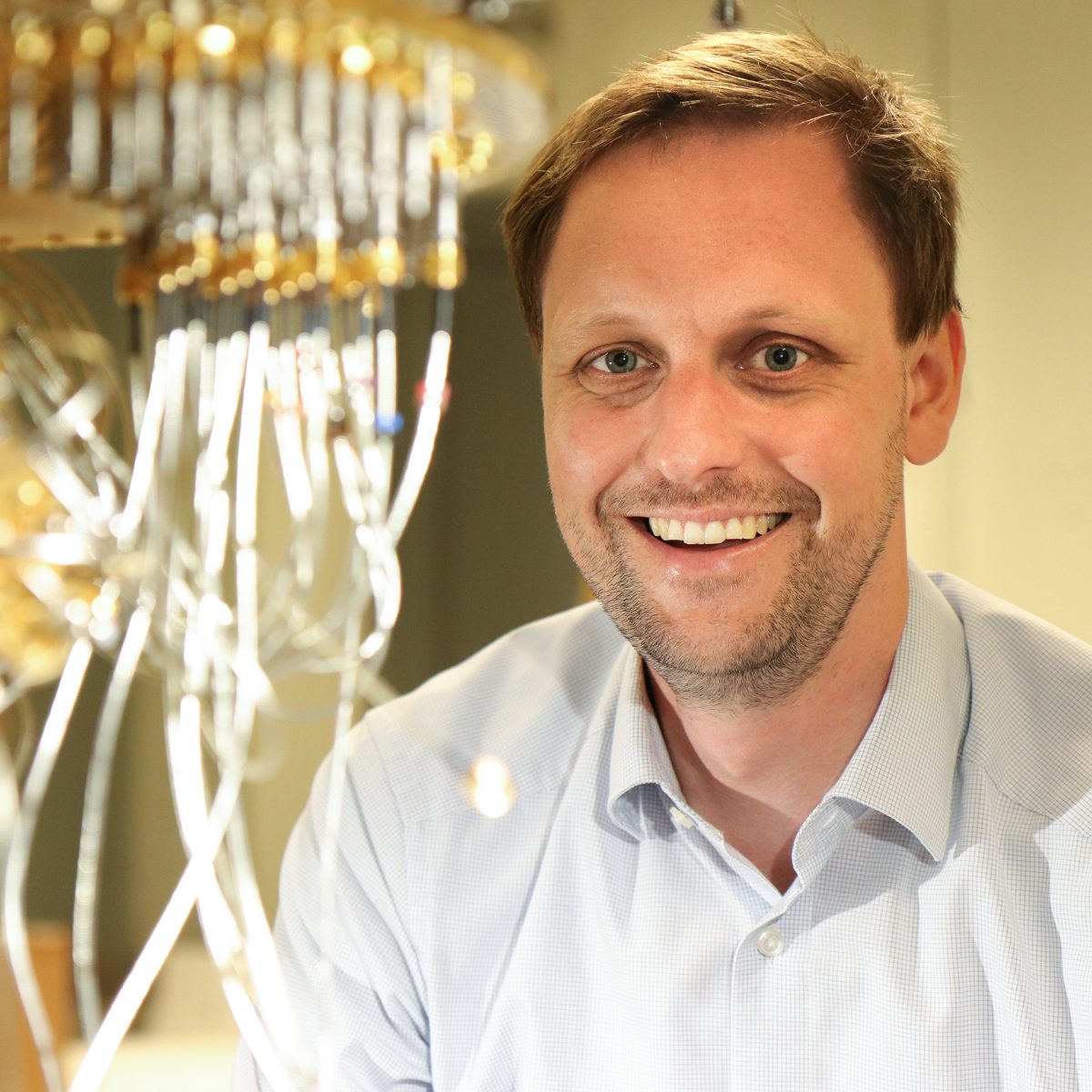 TUM alumnus Dr. Jan Goetz in front of a quantum computer.