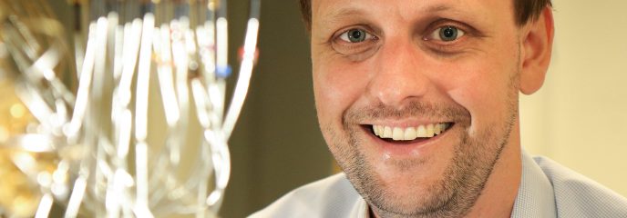 TUM alumnus Dr. Jan Goetz in front of a quantum computer.