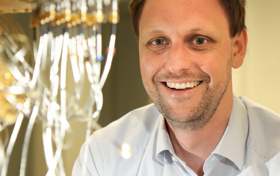 TUM alumnus Dr. Jan Goetz in front of a quantum computer.