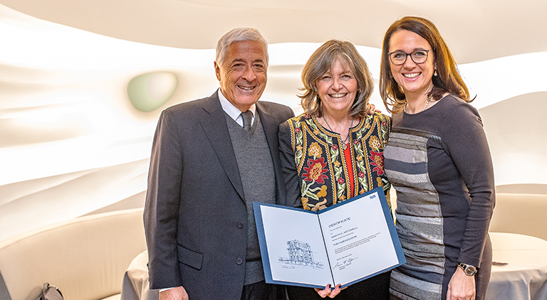 Marta C. Antonelli mit Urkunde und zwei Personen.